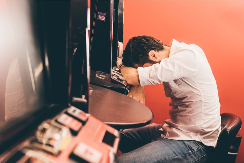 Man leaning on gambling machine