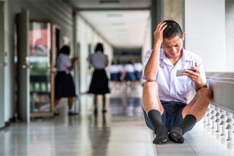 Male southeast Asian student uses smartphone