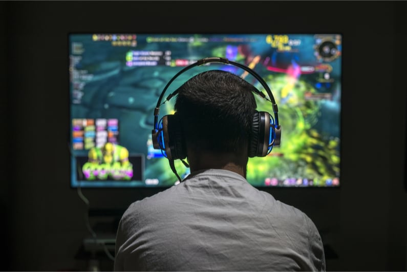 Young gamer wearing headphones and staring at screen